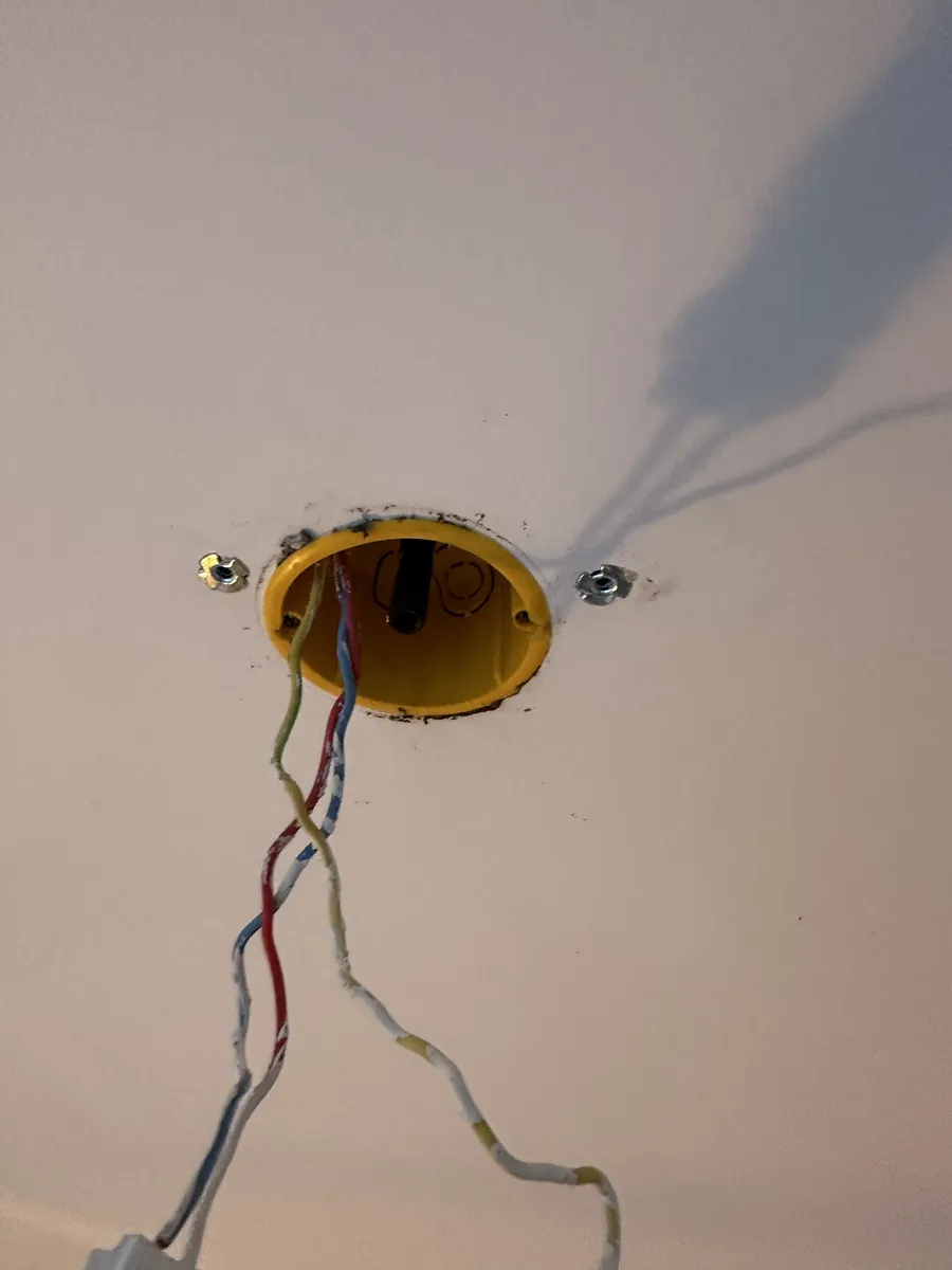 Point lumineux en attente au plafond à L'Haÿ-les-Roses : boîte jaune et fils phase, neutre et terre recouverts de peinture